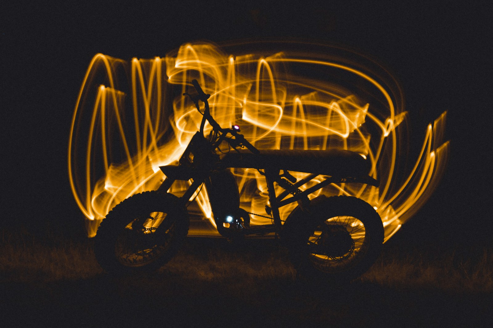 A motorcycle outlined by amber light trails at night